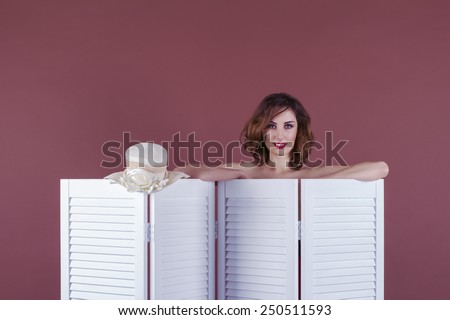 Young sexy woman looking peeping out from behind the folding screen