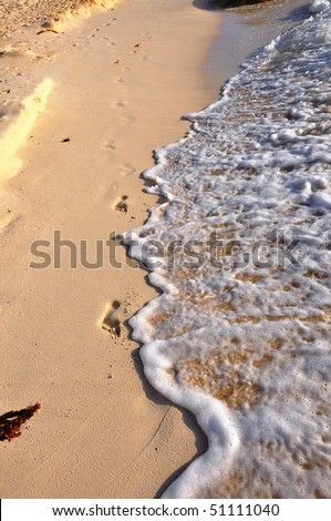 Traces on sand. Prints of feet on sand of sea coast, which in an instant a wave will wash away.