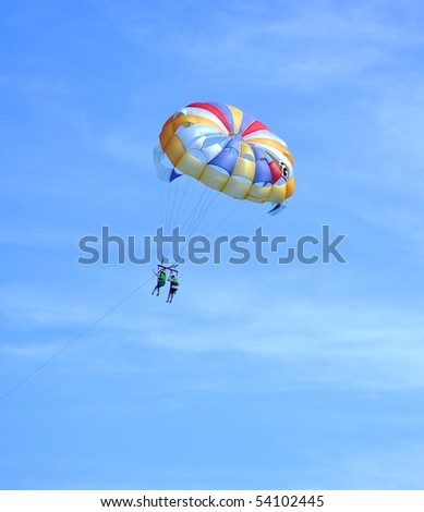 Over the sea on a parachute. A colored parachute over the dark blue sea.