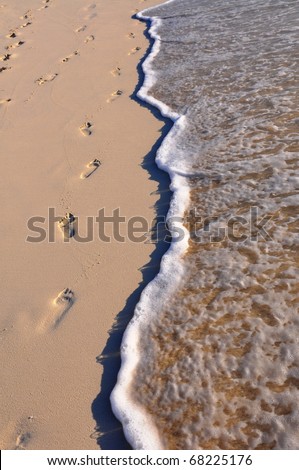 Footprints on sand. Prints of feet on beach sand are washed off by the sea in an instant.