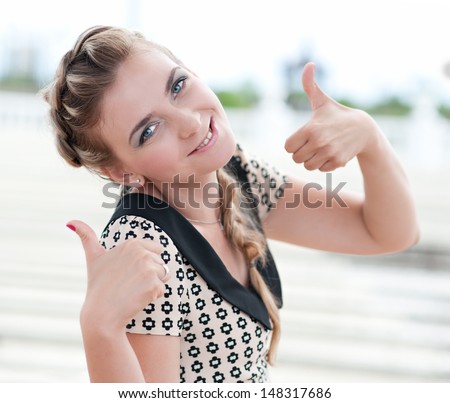 Portrait of cheerful young woman thumbs up with positive attitude