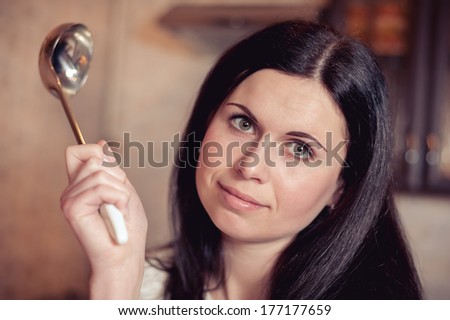 The young brunette with a serving spoon in a hand in kitchen
