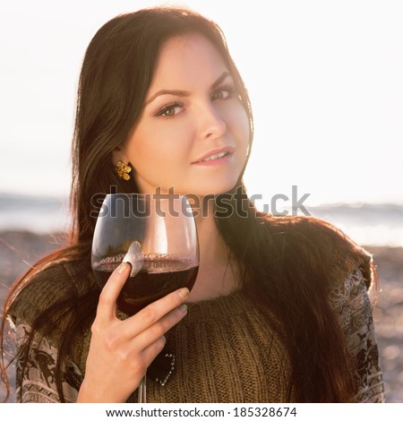 beautiful young woman holding glass of red italian wine. sunset. Photo in color style instagram filters