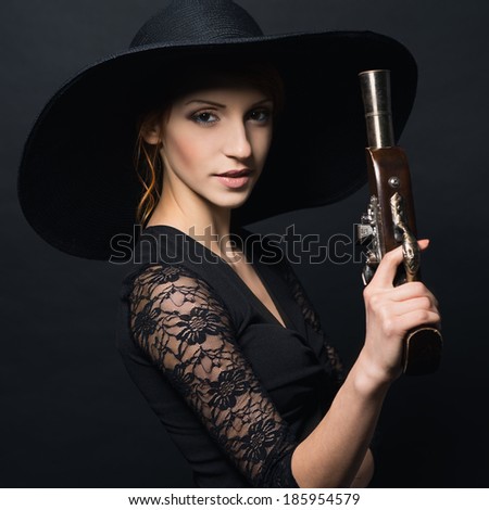 girl pirate with ancient pistol in hand on a black background. Photo in color style instagram filters