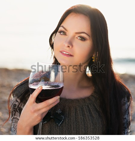beautiful young woman holding glass of red italian wine. sunset. Photo in color style instagram filters