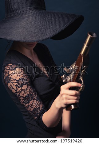 girl pirate with ancient pistol in hand on a black background