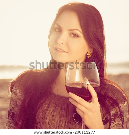 beautiful young woman holding glass of red italian wine. sunset. Photo with instagram style filters