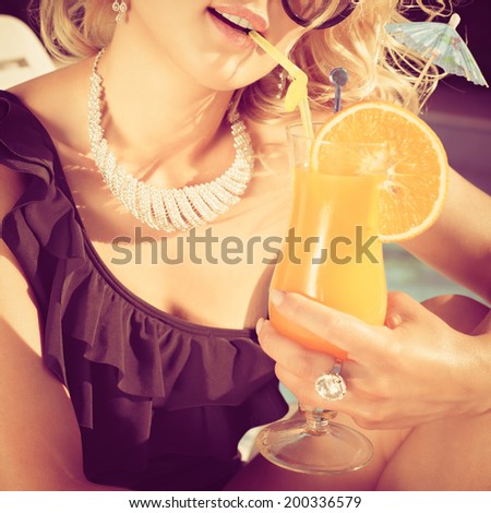 beautiful, suntanned, young woman drinks cocktail, and enjoys in the summer afternoon near the pool. Photo with instagram style filters