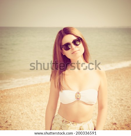 Outdoor fashion warm colors portrait of young sensual happy woman in skirt, bikini and sunglasses. model posing. Vogue style. Photo with instagram style filters