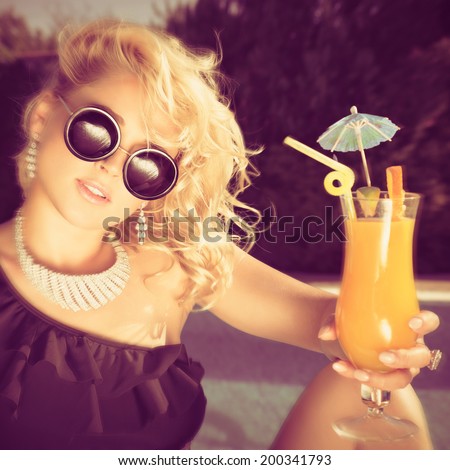 beautiful, suntanned, young woman drinking cocktail, and enjoys in the summer afternoon near the pool. Photo with instagram style filters