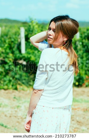 beautiful young woman, walks on a vineyard in a hot summer, sunny day