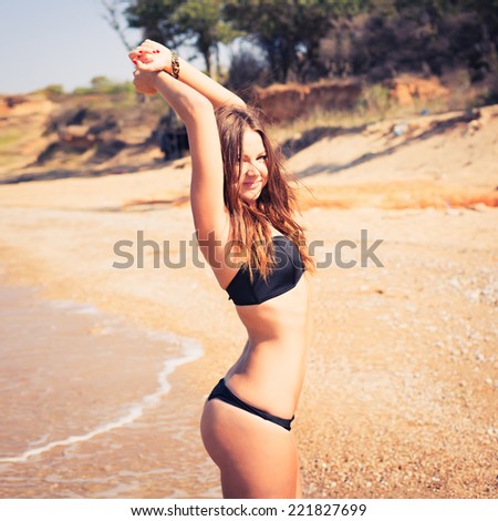 Woman with beautiful body on a tropical beach. beautiful young woman in a black bathing suit relaxing on the beach. Hipster style. Photo with instagram style filters