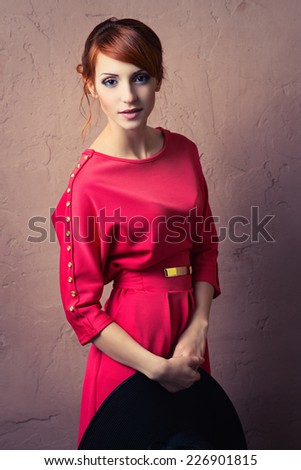 Beautiful young fashionable woman posing in red dress. Looking at camera. Vogue style