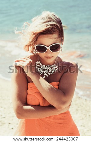 Fashion blonde female in vacation. Posing with cute summer style, pare on bikini, sunglasses and big white necklace