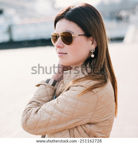 Outdoor lifestyle portrait of woman walking at coast. Fashion style. young woman dressed in branded clothes enjoys warm, spring weather. Photo with instagram style filters