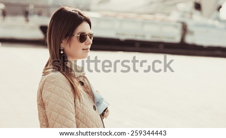 Outdoor lifestyle portrait of woman walking at coast. Fashion style. young woman dressed in branded clothes enjoys warm, spring weather.