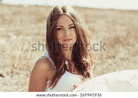 Portrait of the young beautiful smiling woman outdoors enjoying summer sun. wind in hair. girl in a long skirt and with long hair poses in warm spring day.