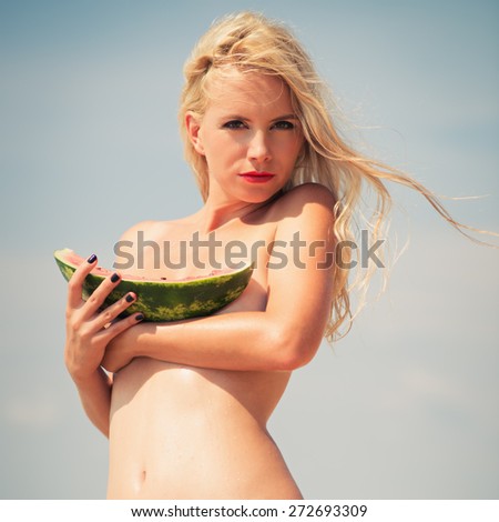 young beautiful girl, attractive blonde, enjoys tropical weather, eats a water-melon, wind develops beautiful long hair. Photo with instagram style filters