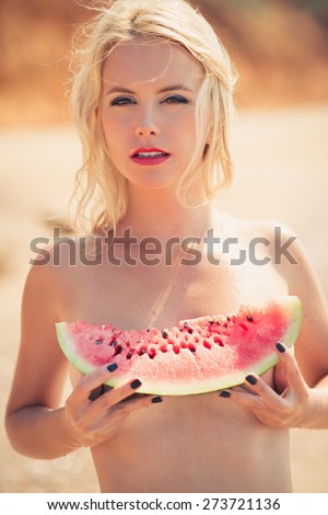young beautiful girl, attractive blonde, enjoys tropical weather, eats a water-melon, wind develops beautiful long hair