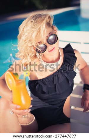beautiful, suntanned, young sexy woman drinking cocktail, and enjoys in the summer afternoon near the pool. young sexy fashion woman drinking cocktail