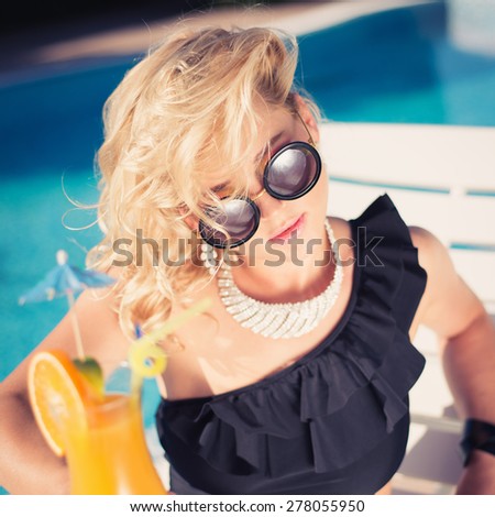beautiful, suntanned, young sexy woman drinking cocktail, and enjoys in the summer afternoon near the pool. young sexy fashion woman drinking cocktail. Photo with instagram style filters