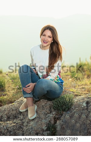 Smiling girl enjoys fine warm spring weather highly in mountains against the sea. . Smiling girl enjoys fine warm spring weather highly in mountains against the sea