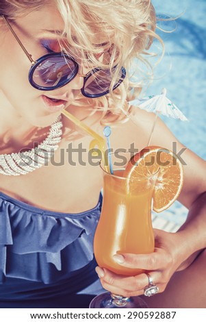 beautiful, suntanned, young sexy woman drinking cocktail, and enjoys in the summer afternoon near the pool