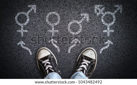 A person standing on asphalt road with gender symbols of male, female, bigender and transgender.  Concept of choice or gender confusion or dysphoria.