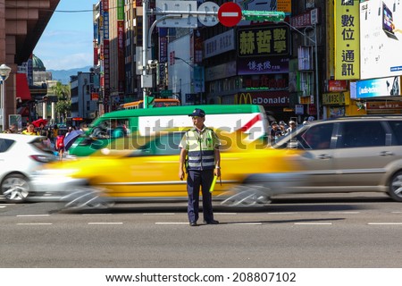 TAIPEI, TAIWAN - JUL 16 : A traffic warden stands in the middle of a busy Taipei road directing early rush hour traffic July 16, 2013. Traffic congestion is the top public grievance in Taipei City.