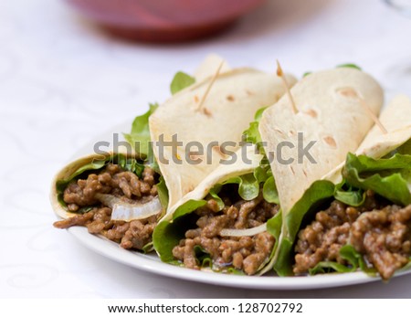 Three simple Burritos filled with meat, onion and salad