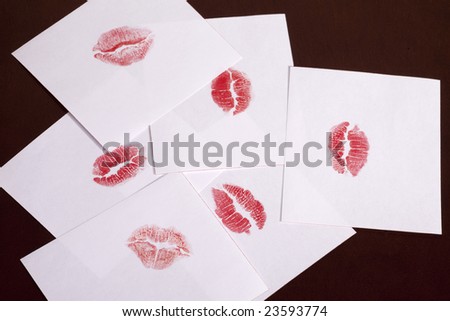 A bunch of note papers with lipstick kiss impressions laying on a desk. Pile of kissing.