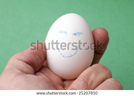 An egg decorated in blue crayon with a happy smiley face.