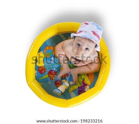 Baby boy wearing a sun hat and playing inside a plastic pool with toys on a white background