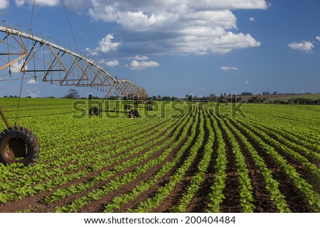 Industrial irrigation equipment on farm field under a blue sky in Brazil.