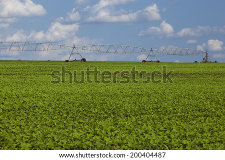 Industrial irrigation equipment on farm field under a blue sky in Brazil.