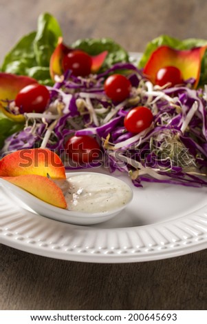 Salad dish with grape tomatoes, lettuce and red cabbage and sauce. Coleslaw
