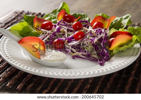Salad dish with grape tomatoes, lettuce and red cabbage and sauce. Coleslaw