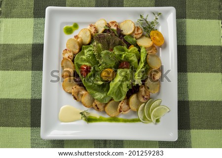A dish of king scallop with potatoes and salad in a plate seen from above