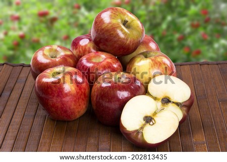 Some apples over a wooden surface on a apple field background