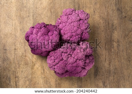 Purple cauliflowers over a wooden surface seen from above