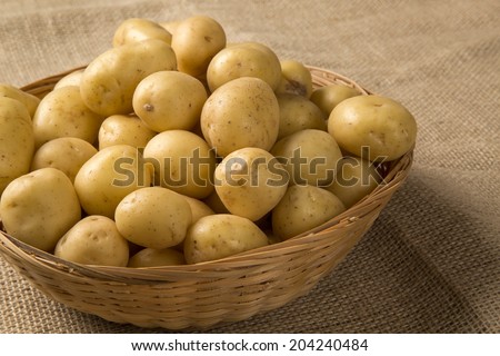 Some small potatoes in a basket over a burlap bag