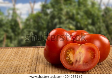 Some tomatoes over a wooden surface on a tomato field as background
