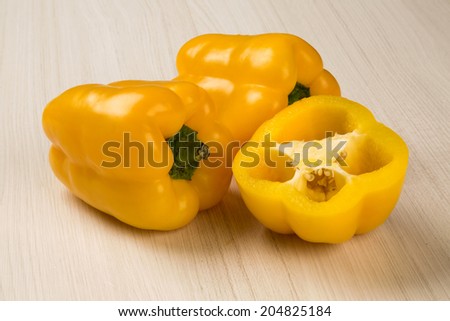 Some yellow peppers over a wooden surface