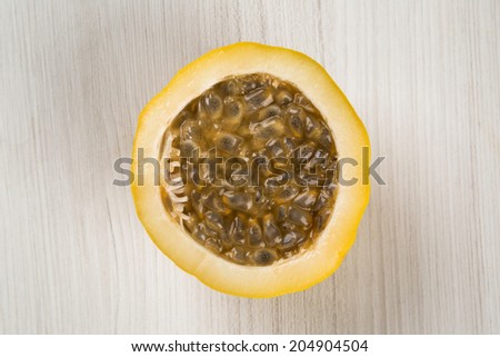 A passion fruit cut in a half over a wooden surface seen from above