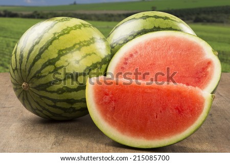Ripe watermelons on wicker tray on table on wooden background