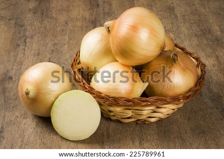 Assorted farm fresh onions on a rustic wooden table with spring onions