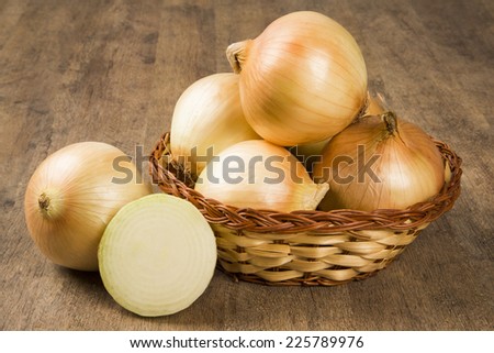 Assorted farm fresh onions on a rustic wooden table with spring onions