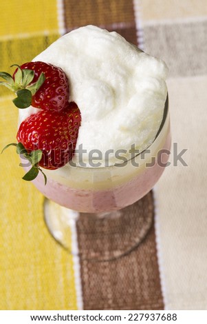 Berry smoothie or milkshake in a tall glass made from a blend of fresh strawberries and raspberries with frozen yoghurt or ice cream for a refreshing summer beverage