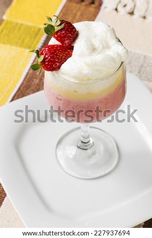 Berry smoothie or milkshake in a tall glass made from a blend of fresh strawberries and raspberries with frozen yoghurt or ice cream for a refreshing summer beverage