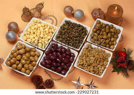Variety of green, black and mixed marinated olives in olive tree dish on wooden table. Above point of view